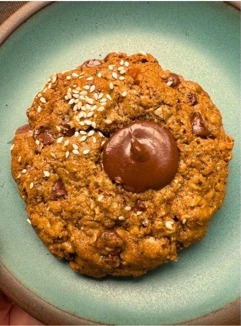 A sesame-topped granola cookie with a chocolate center on a green plate.